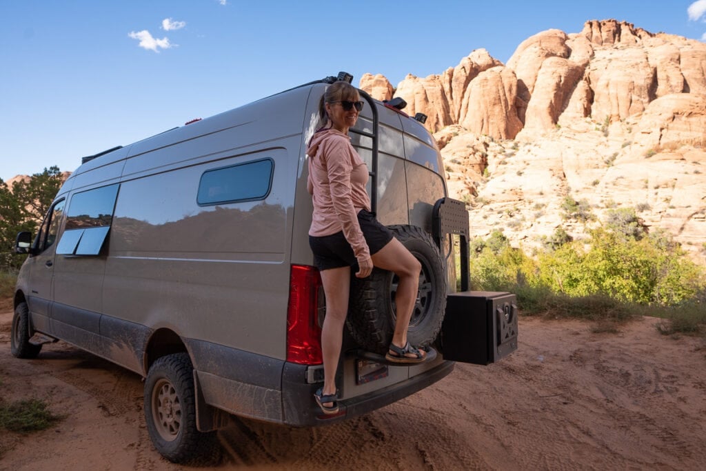 Kristen Bor climbing ladder on back of Sprinter van